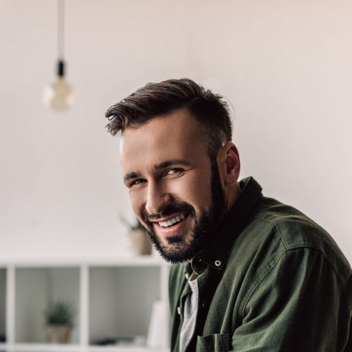 bearded businessman in casual clothing smiling at camera in mode