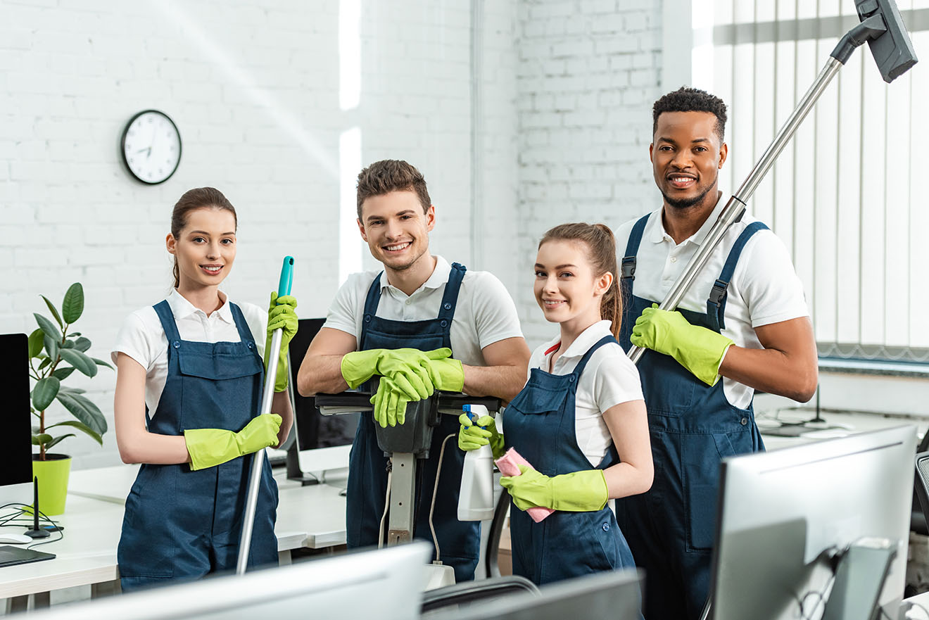 happy multicultural cleaners looking at camera while standing wi